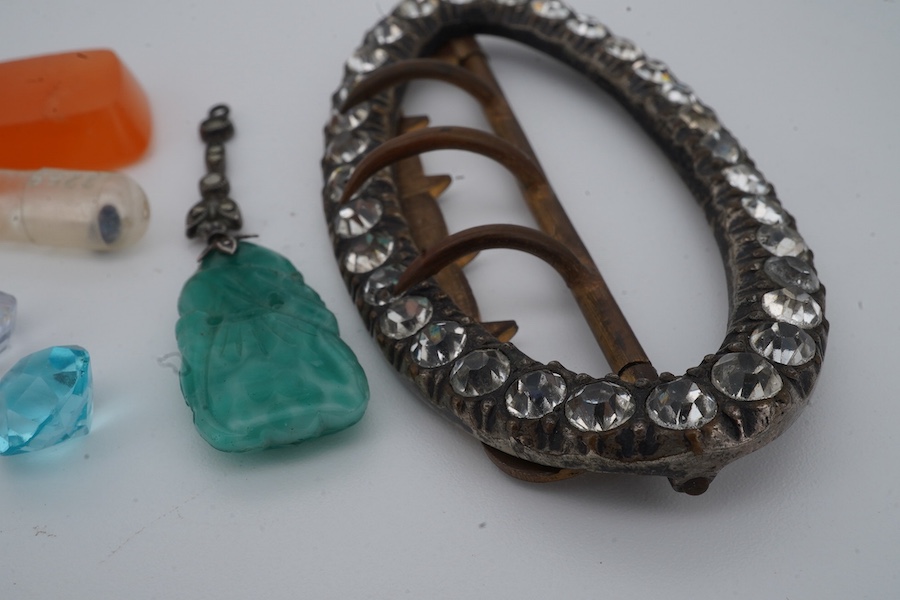 A collection of jewels and a loose sapphire, comprising: a shoe buckle set with colourless pastes, length 6.8cm; a green paste and marcasite pendant imitating jadeite; a polished slab of carnelian; a loose cushion-shaped